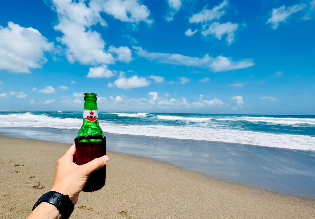Ouders geniete van een Bintang terwijl kinderen spelen op het strand van Canggu, Bali