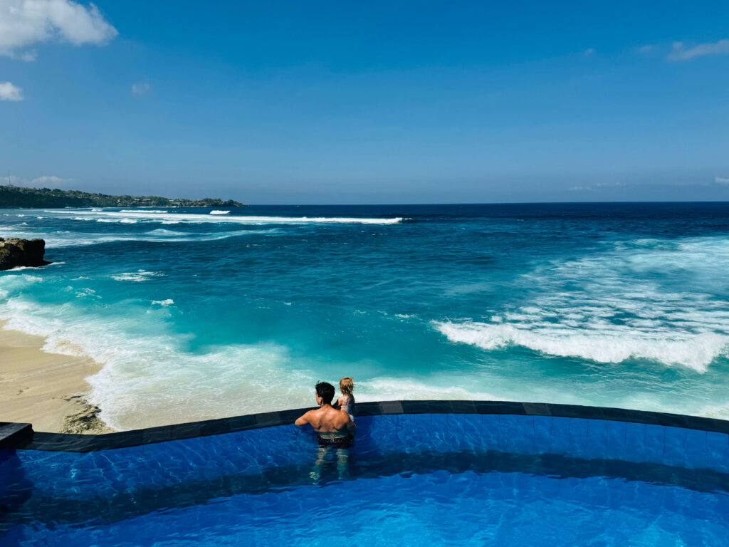 Kinderen spelen in zwembad terwijl ouders genieten van het uitzicht op dream beach op Nusa Lembongan, Bali