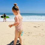 Young child playing on Dreamland Beach in Uluwatu, Bali, surrounded by dramatic cliffs and ocean views