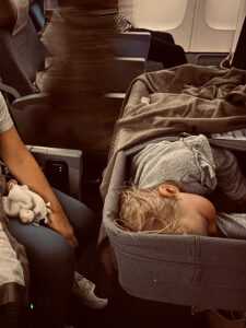 baby sleeping in airplane bassinet going on a family vacation