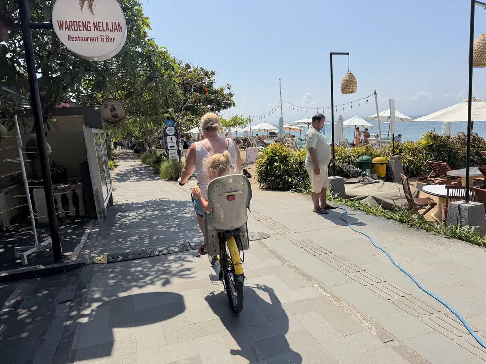 Mother and daughter riding together on a bike along the Sanur beach path