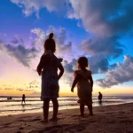 Kids watching sunset at Seminyak beach, Bali
