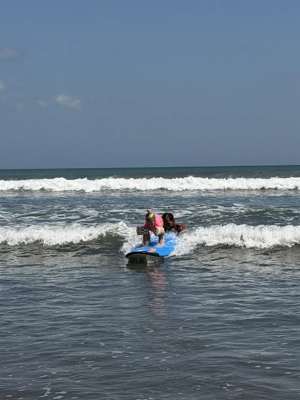 4-year-old daughter riding a surfboard during a kids’ surf lesson in Bali