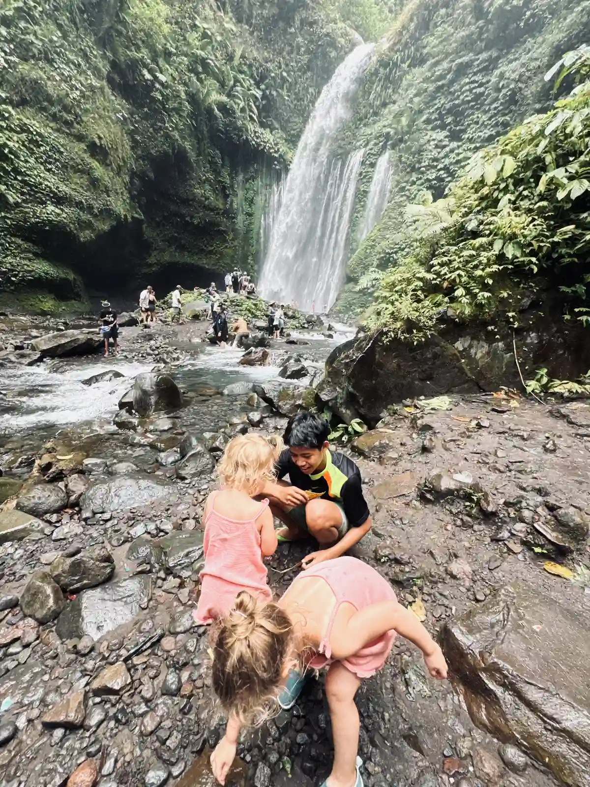 Lokale gids speelt met onze kinderen bij de Tiu Kelep waterval