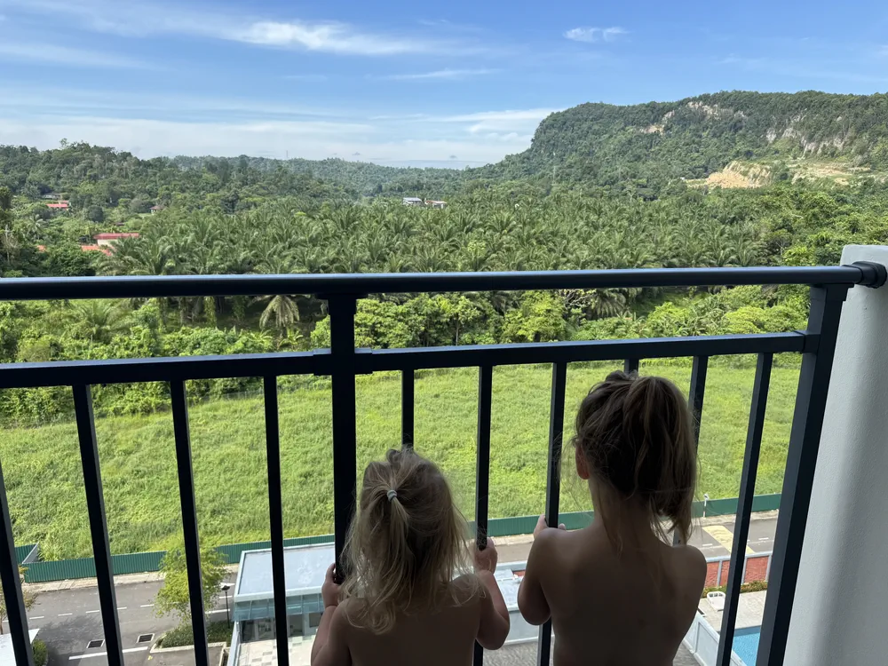 Kinderen genieten van het uitzicht vanuit ons appartement in Sandakan, vooral van het zwembad beneden