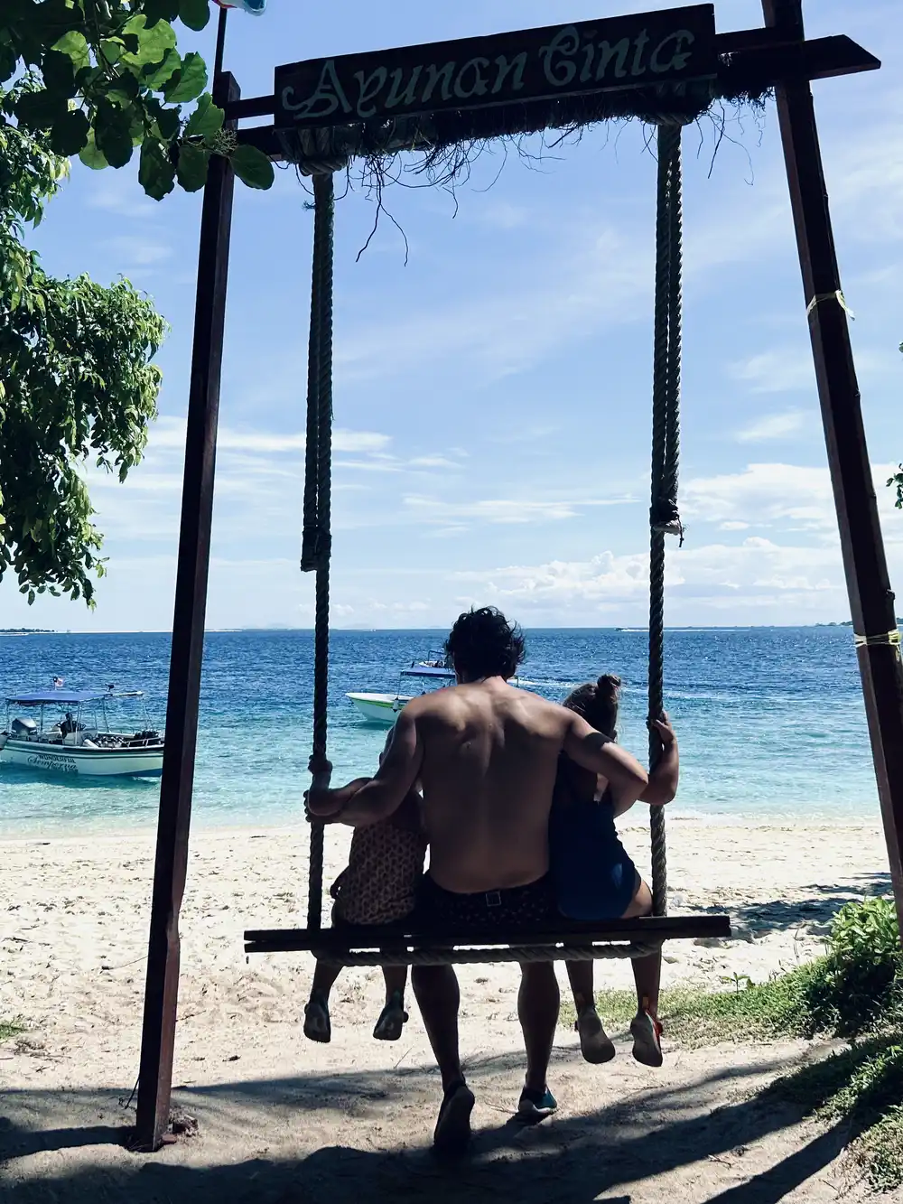 Father and daughters on a swing at Mataking Island near Semporna