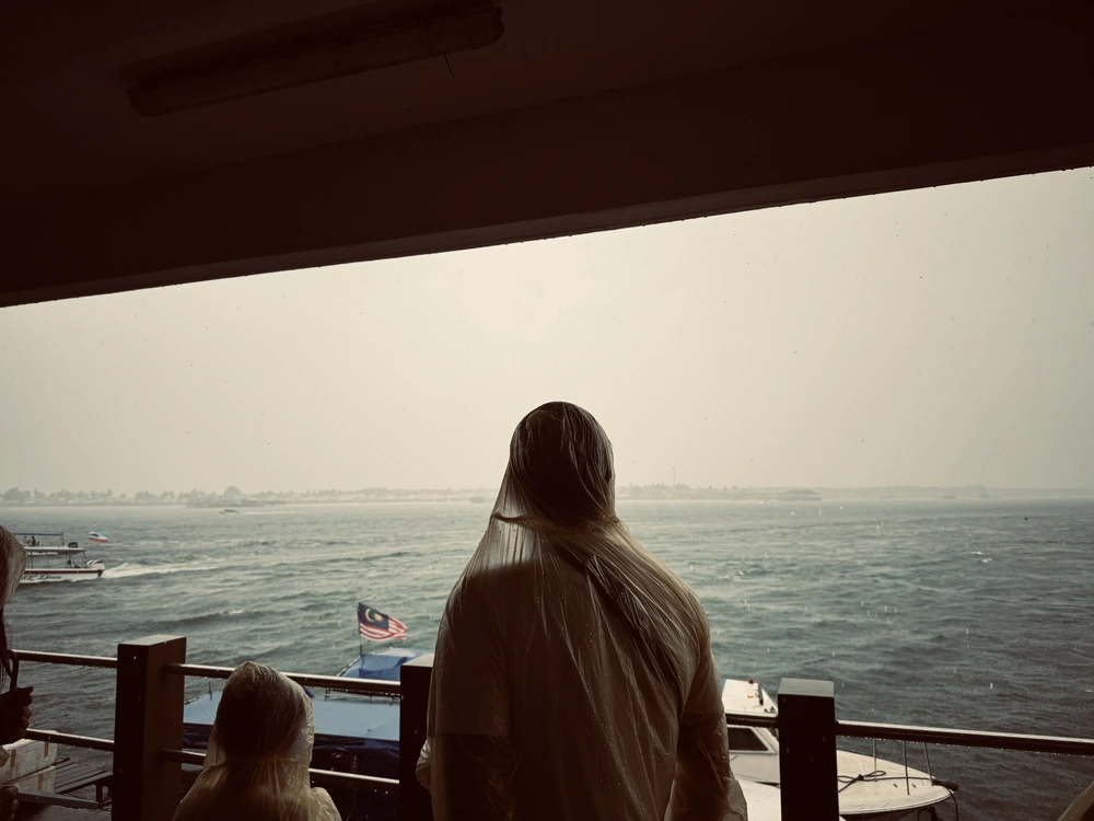 Wachten op onze boot in Semporna in een tropische regenstorm met kinderen