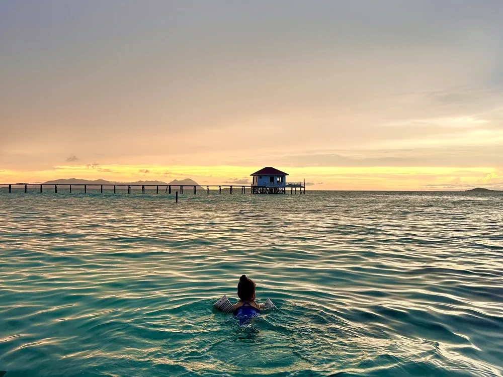 Zwemmen met kinderen tijdens zonsondergang in een over water resort in Semporna