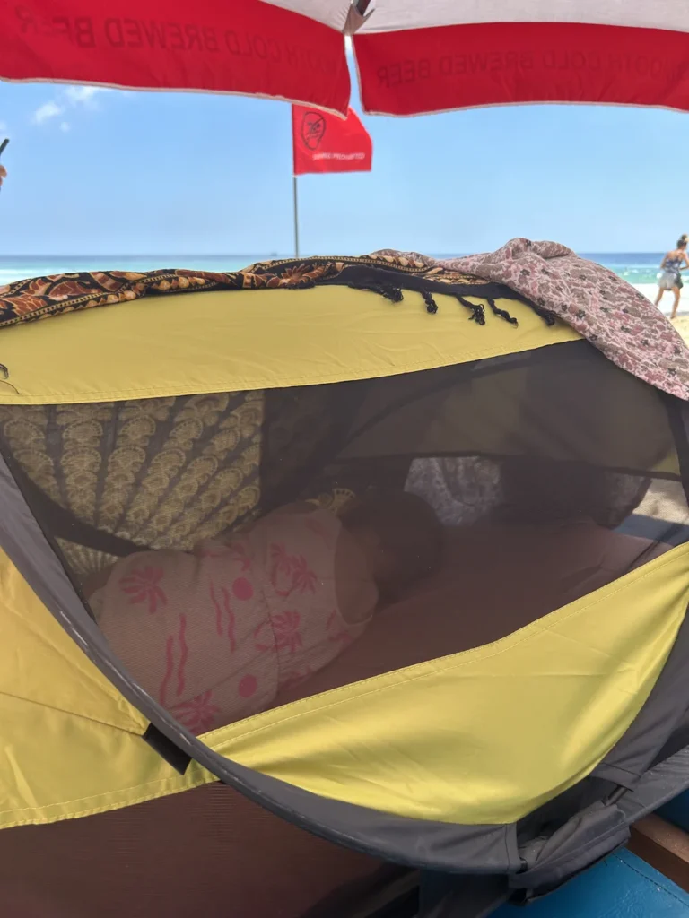 Kinderen slapen in een reisbedje (Deryan Travel Cot) op het strand