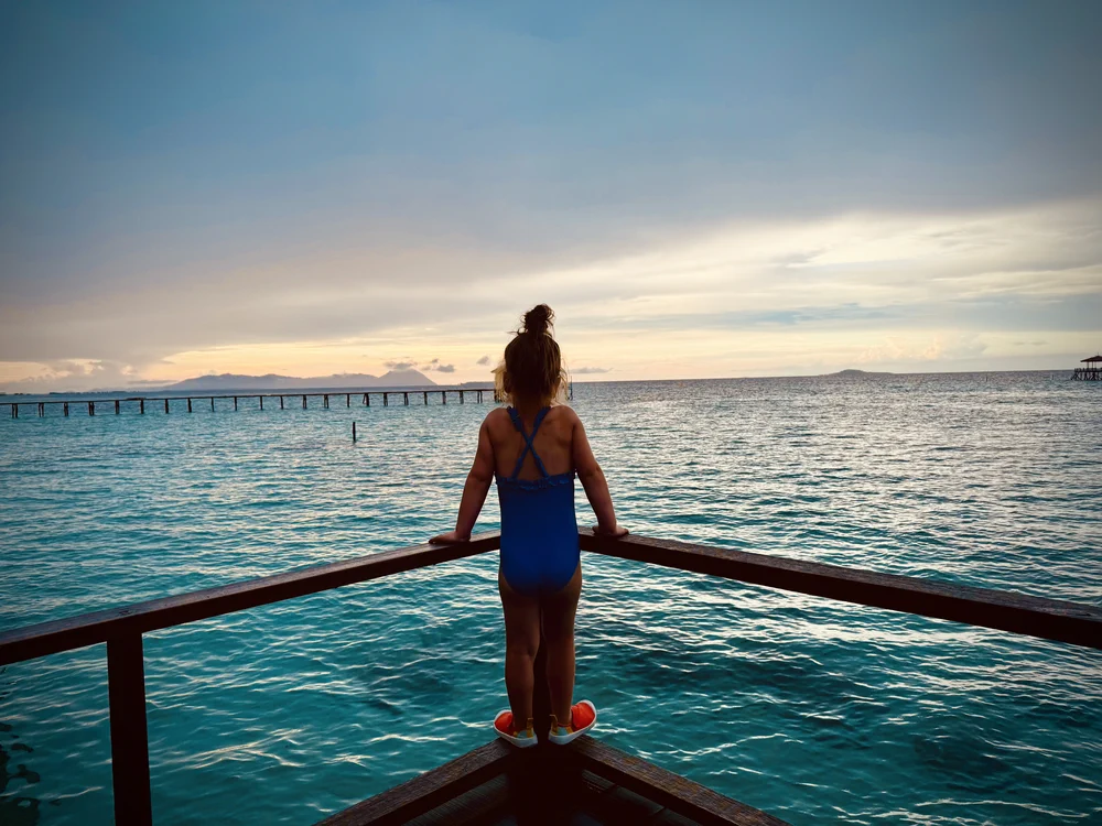 Child watching sunset from an overwater bungalow near Semporna, Sabah, Borneo