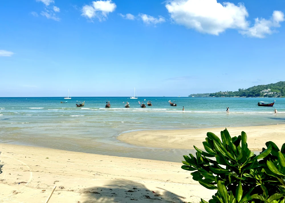 Phuket strand tijdens het droge seizoen met een gezin dat in de rustige zee speelt
