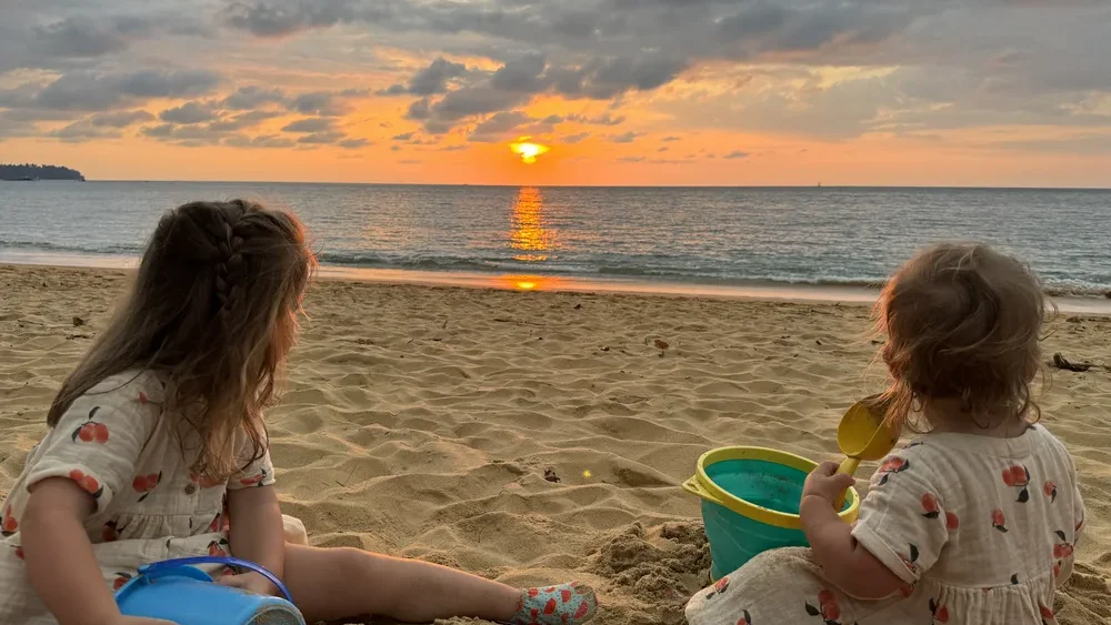 Toddler and baby ejoying the sunset and playing in the sand on Khao Lak beach