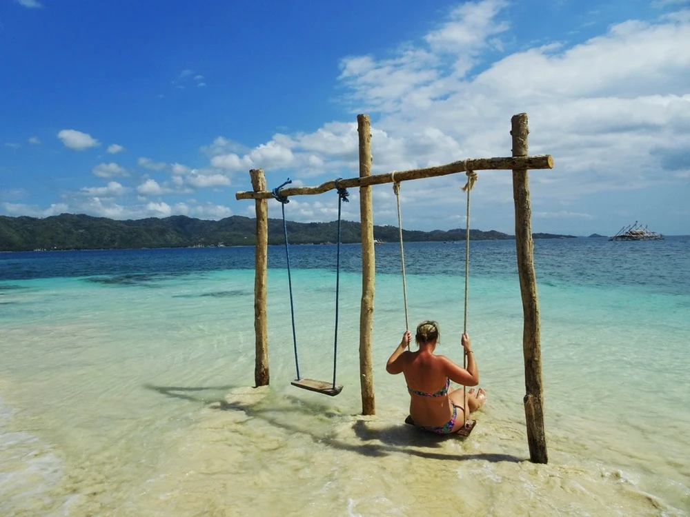 Wooden swing on a quiet tropical beach in the Southwest Lombok Secret Gilis with turquoise water