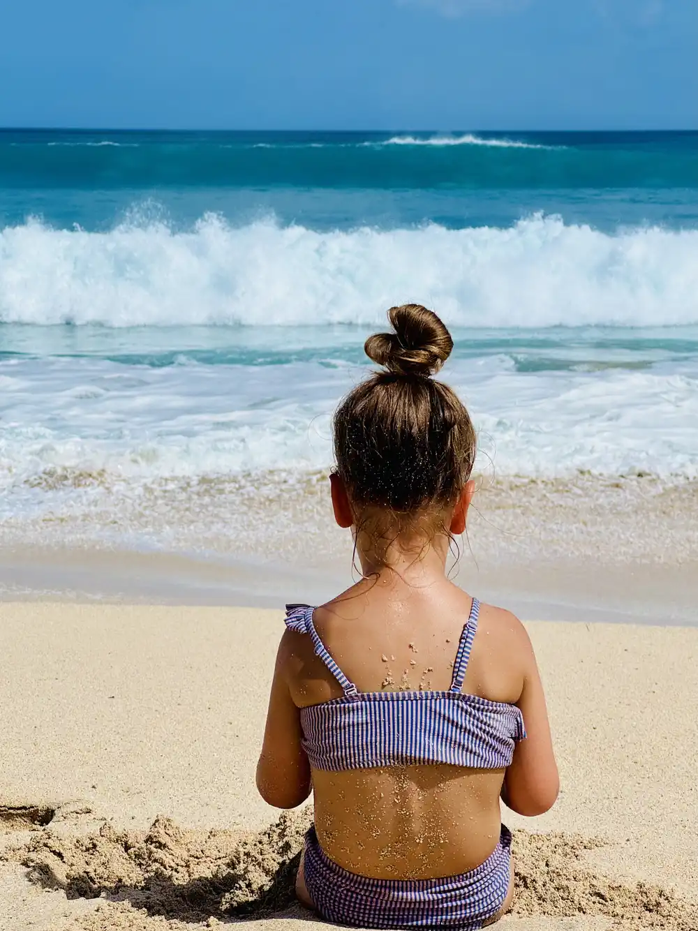 Child watching large waves at Dreamland Beach in Uluwatu, Bali