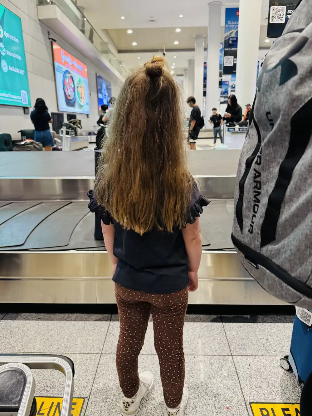 Toddler waiting at the baggage carousel after an international flight