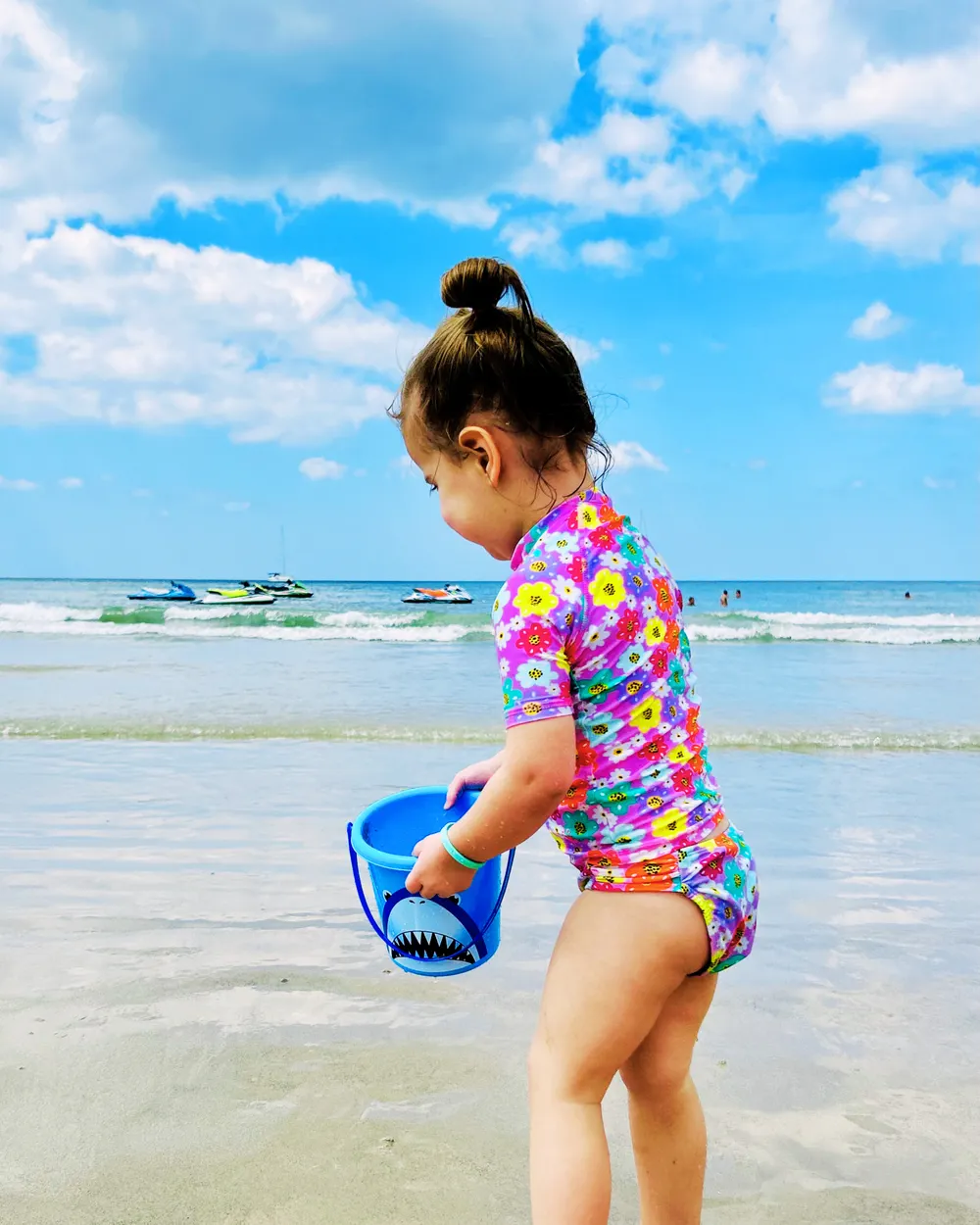 Toddler playing in the sea with a bucket and shovel during a Phuket beach day