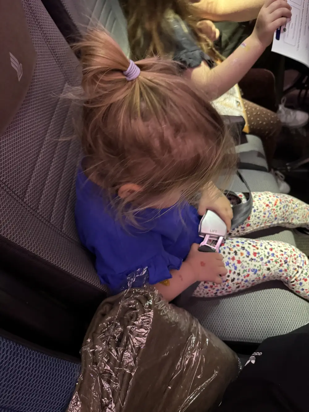 Toddler fastening an airplane seatbelt before takeoff