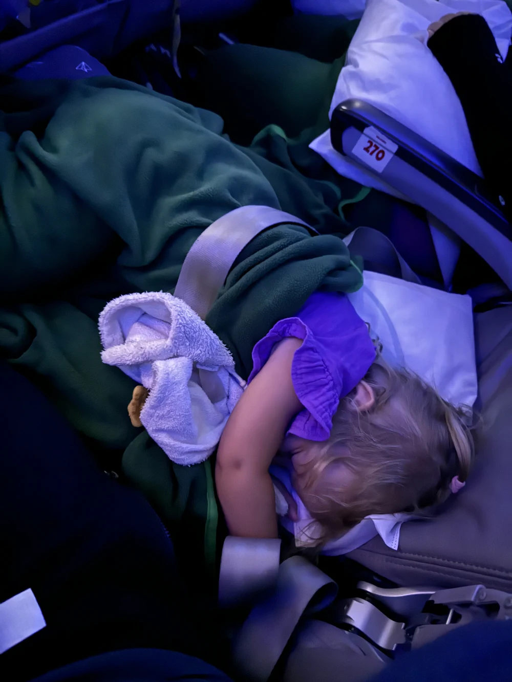 Toddler sleeping on an inflatable airplane bed during a long flight