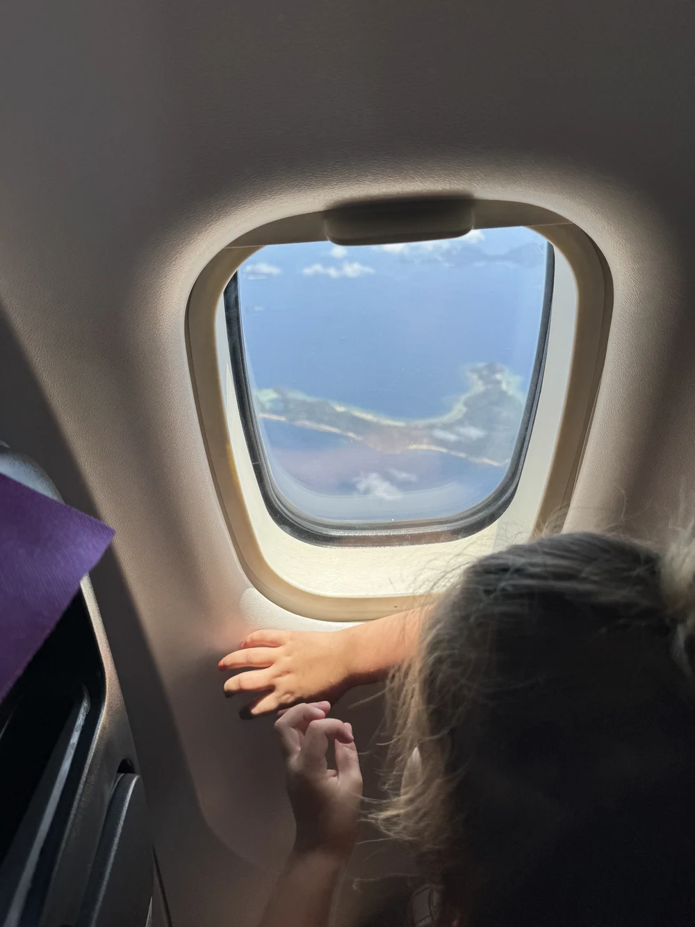 Toddler looking out the airplane window during landing