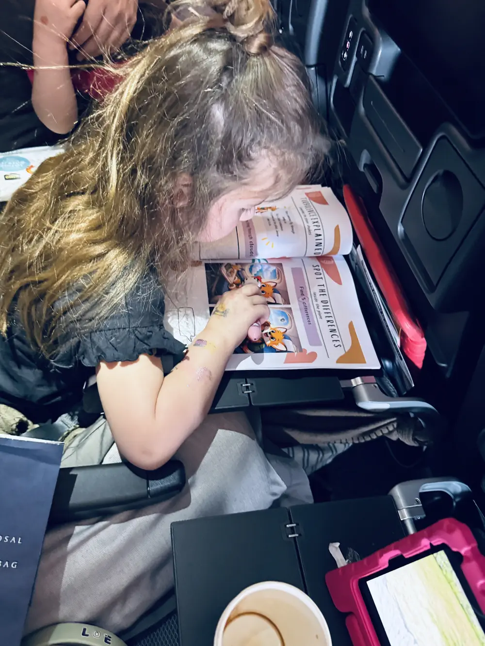 Toddler using the Little Passport Crew Travel Activity Book on a plane