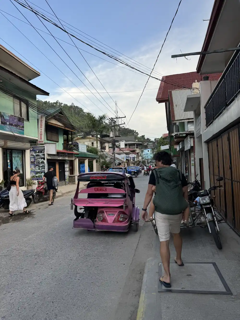 Father carrying a toddler in a baby carrier during a family trip to El Nido, Philippines