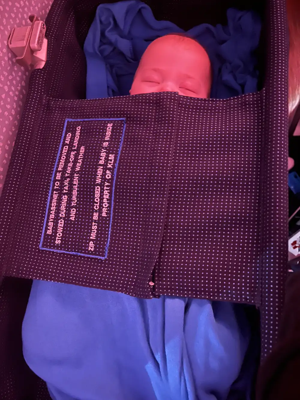 Baby sleeping in an airplane bassinet during a long-haul flight