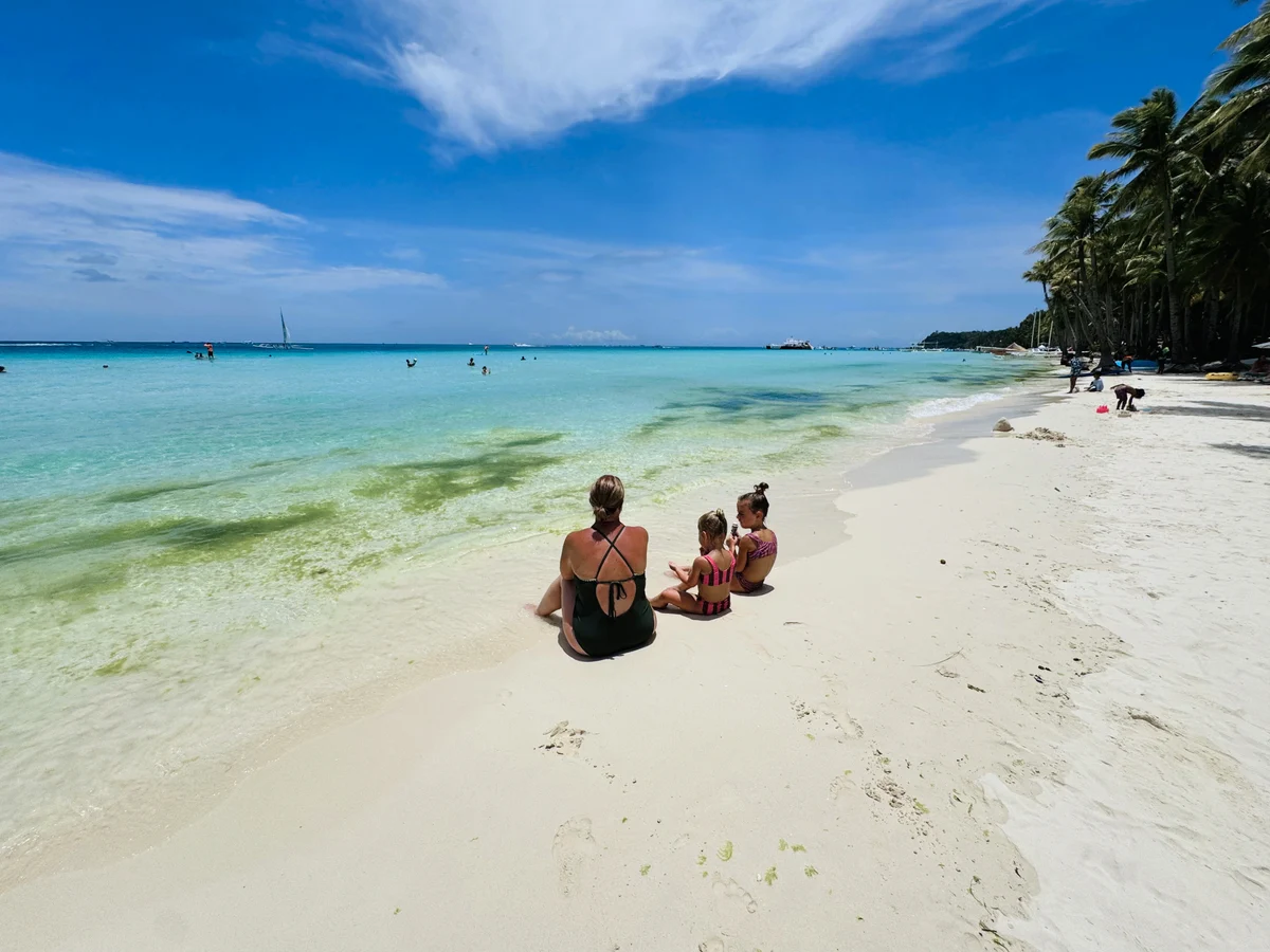 Mother and daughters relaxing on White Beach in Boracay, Philippines