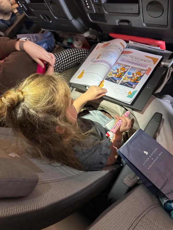 Our daughter using the travel activity book on a flight to the Philippines