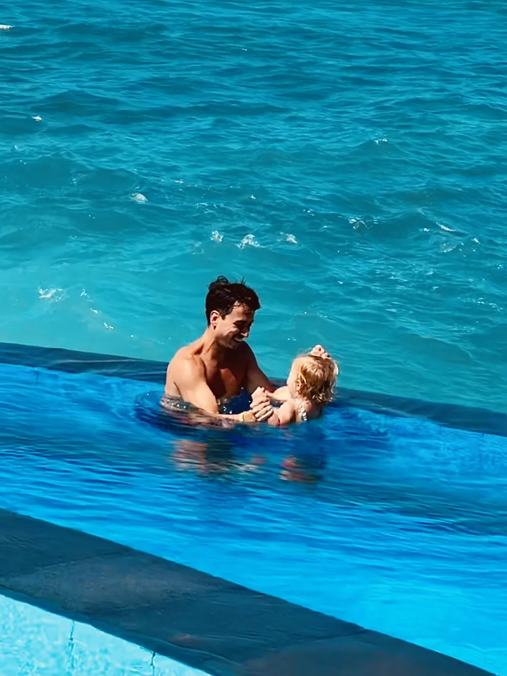 Father and daughter in a pool overlooking Dream Beach on Nusa Lembongan