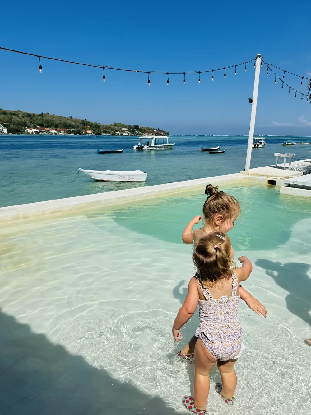 Two children swimming in a pool overlooking the sea between Nusa Lembongan and Nusa Ceningan
