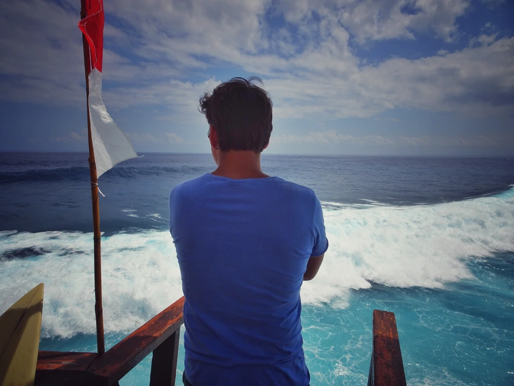 Traveler watching surfers from a viewpoint on Nusa Ceningan